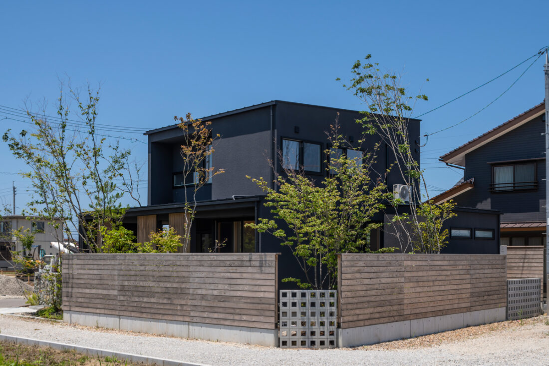 黒の窓枠と濃い目の外壁と木目の組み合わせがおしゃれな家の実例（斜めから）